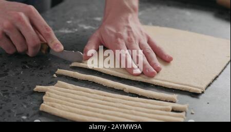 man cutting flat dough with knife, wide photo Stock Photo