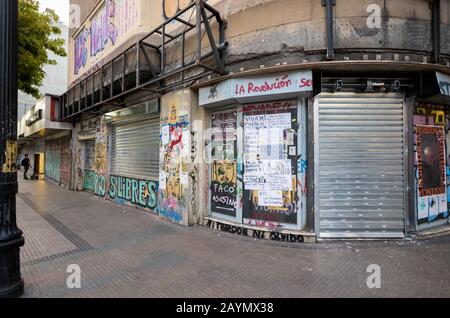 Graffiti and posters from the political unrest and protests on shuttered shops in Lastarria, Central Santiago, Metropolitan Region, capital of Chile Stock Photo