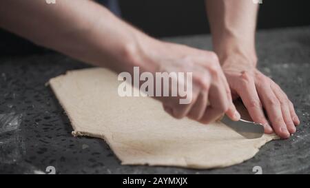 man cutting flat dough with knife, wide photo Stock Photo