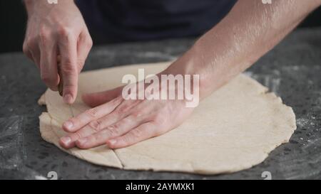 man cutting flat dough with knife, wide photo Stock Photo