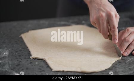 man cutting flat dough with knife, wide photo Stock Photo