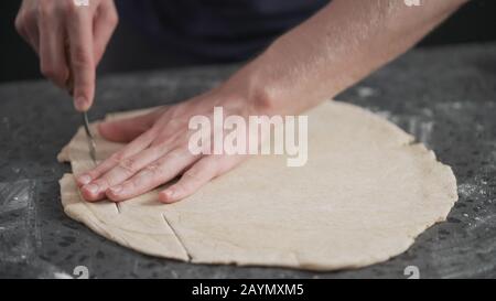 man cutting flat dough with knife, wide photo Stock Photo