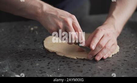 man cutting flat dough with knife, wide photo Stock Photo