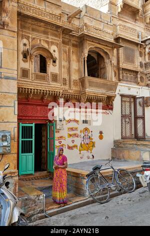 local woman in front of colorful Haveli in Jaisalmer, Rajasthan, India Stock Photo