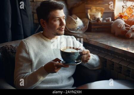 young gorgeous man belives in real love, waiting for his girlfriend, close up photo, evening with yummy latte, let the world wait for you Stock Photo
