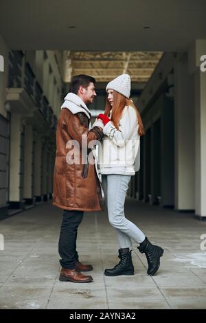 young happy man and woman standing in the street, having conversation, full length side view photo. I love you, baby Stock Photo