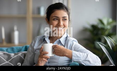Happy indian woman drink warm tea relaxing at home Stock Photo