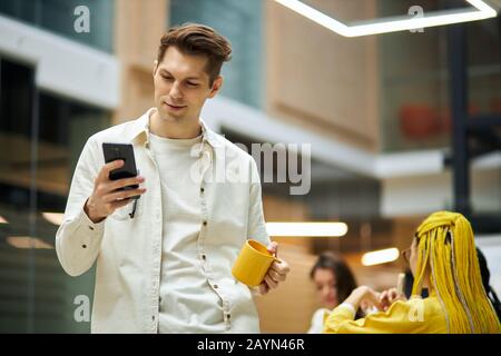 Smiling handsome young man using smart phone, texting message, typing sms, surfing the net, internet. close up photo. blurred background. copy space Stock Photo