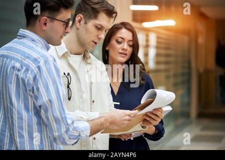 three business people analyzing the report, journalist looking at the srticle, searching necessary information, team work, paper work Stock Photo