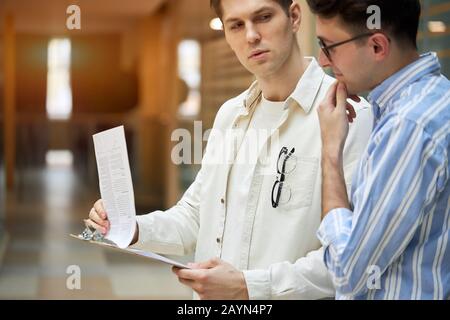 clever handsome guys searching, looking for mistakes in the document, business people in stylish shirts solving, overcoming problems . let me think Stock Photo
