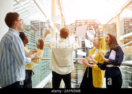 business people supporting crazy male colleague. back view photo Stock Photo
