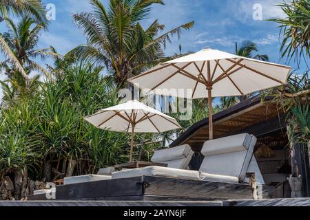 Sun loungers and white fabric umbrellas on the beach. Bali, Indonesia. Stock Photo