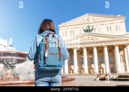 Rear view of a woman with a backpack admiring the majestic architecture and view of the Bolshoi Theater, tourism in Moscow and Russia concept Stock Photo