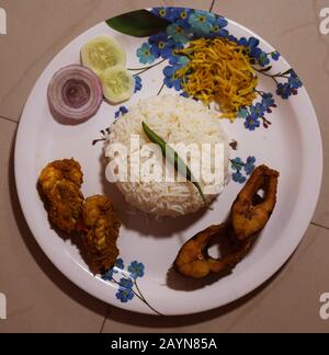 Bengali food - Delicious homemade Bengali Fish Thali or dish consists of Rohu fish fry along with Prawn Malai Curry, Rice, Crispy potato fry and salad Stock Photo