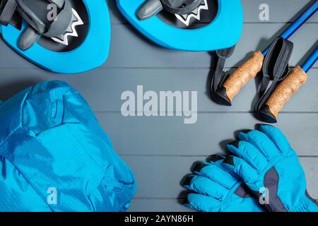 Flat lay top view on winter hiking and snowshoeing equipment with blue backpack and gloves with trekking sticks Stock Photo