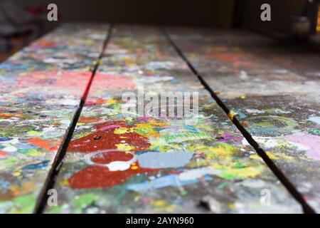 Artists workshop or studio bench covered with splattered paint built up in authentic texture on painted surface Stock Photo