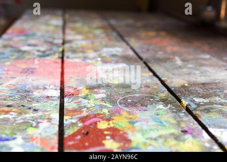 Artists workshop or studio bench covered with splattered paint built up in authentic texture on painted surface Stock Photo