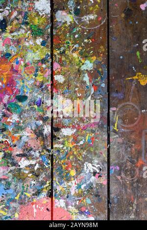 Artists workshop or studio bench covered with splattered paint built up in authentic texture on painted surface Stock Photo