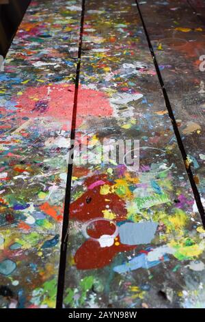 Artists workshop or studio bench covered with splattered paint built up in authentic texture on painted surface Stock Photo