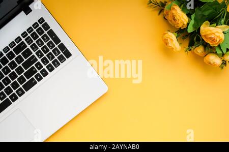Black-white laptop keyboard, yellow flowers on an orange background. Flat lay. Top view. Copy space Stock Photo