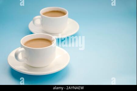 Two white cups coffee with milk, light blue background, side view. Americano. Copy space Stock Photo