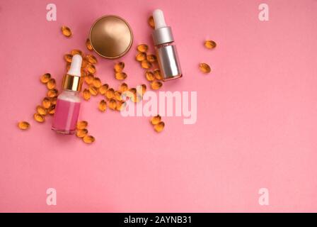 Bottle of cream with oil capsules, cosmetic serum with a pipette on a pink background. Space for text. Flat lay. Top view Stock Photo