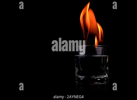 Glass with vodka and fire flame on black background Stock Photo