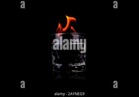 Glass with vodka and fire flame on black background Stock Photo