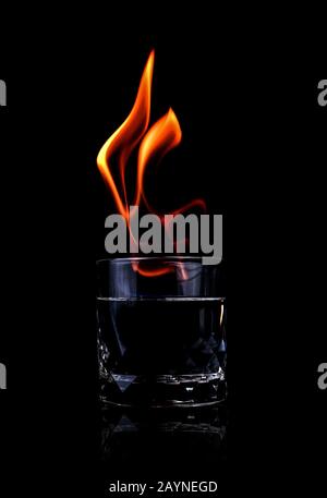 Glass with vodka and fire flame on black background Stock Photo
