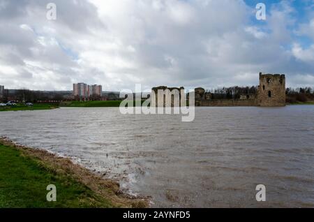 Flint Castle in Flintshire, North Wales with an unusually high spring tide. The flood water of the nearby River Dee approaches the walls of the castle Stock Photo