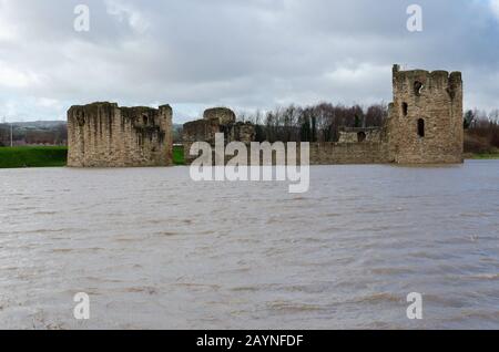 Flint Castle in Flintshire, North Wales with an unusually high spring tide. The flood water of the nearby River Dee approaches the walls of the castle Stock Photo