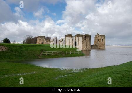 Flint Castle in Flintshire, North Wales with an unusually high spring tide. The flood water of the nearby River Dee approaches the walls of the castle Stock Photo
