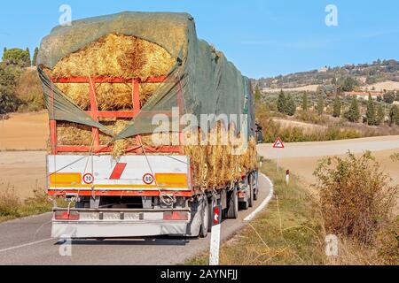 Heavy truck with load of hay on a rural tuscany road Stock Photo