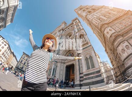 Happy asian woman tourist with raised hands at the old town square of Florence near Santa Maria Del Fiore Cathedral. Travel in Italy concept Stock Photo