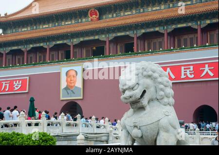 A statue of a stone lion is guarding the Forbidden City in Beijing, China with a Mao picture over the gate in the background. Stock Photo