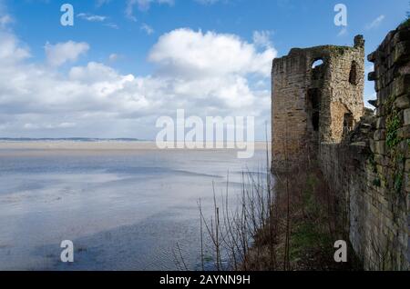 Flint Castle in Flintshire, North Wales with an unusually high spring tide. The flood water of the nearby River Dee approaches the walls of the castle Stock Photo
