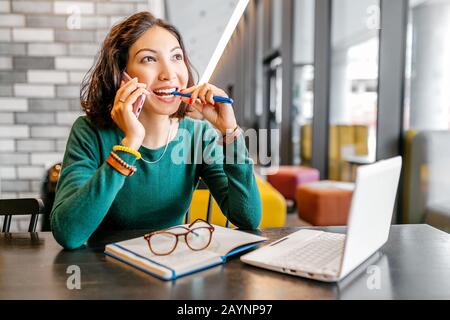 Happy asian woman using notebook computer and smartphone while thinking about new ideas for business or education Stock Photo