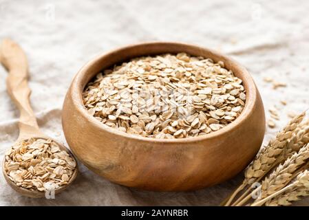 Rolled oats, oat flakes in wooden bowl. Healthy food, dieting, breakfast cereals concept Stock Photo