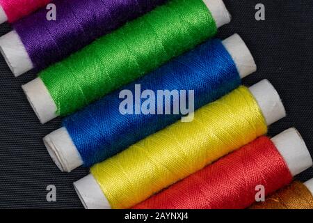 Cones with bright colored sewing thread on black textured surface Stock Photo