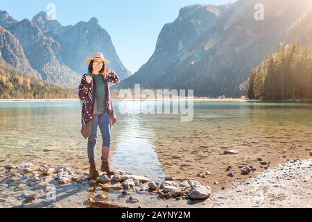 Happy young traveler woman having fun on a coast of a Dobbiaco lake in Dolomites Alps, Italy Stock Photo