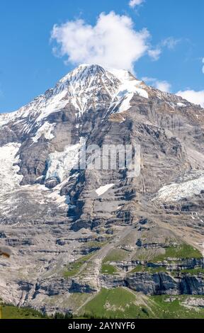 Beautiful Swiss Alps views on the yellow train of the Wengernalp Railway from Wengen to Kleine Scheidegg with Jungfraujoch peaks behind, Switzerland. Stock Photo