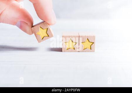 3 Star Ranking Formed By Wooden Blocks And Arranged By A Male Finger On A White Table Stock Photo