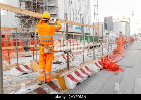 Construction worker in orange safety uniform and helmet working at the city street Stock Photo