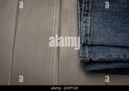 Denim pants with gold stitching on gray wooden background Stock Photo