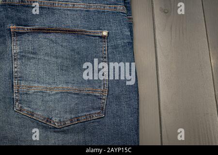 Back pocket of a washed blue denim trousers with gold stitching on gray wooden background Stock Photo