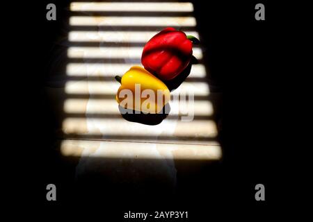 Yellow and Red Paprika with with striped shadow lines from a window to show concept of gastronomy, nutrition and veganism Stock Photo