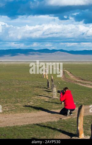 A tourist is photographing the Ungut complex, a Turkik monument ensemble consisting of man stones and numerous tombs from the 6-8th centuries AD in Hu Stock Photo