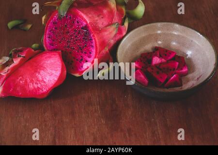 Sliced red dragonfruit against a wooden background showing concept of summer, healthy food, veganism and healthy lifestyle Stock Photo