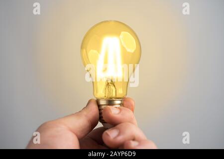 Caucasian man holding glowing incandescent light bulb. Idea or thought abstract concept. Stock Photo