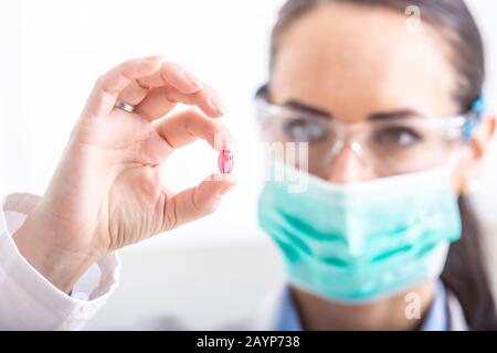 Young female scientist holding a red pill - close-up. Stock Photo